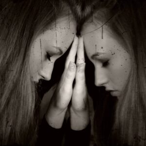 Une femme triste en introspection, front collé sur un miroir, outil qui lui permet de voir l'ego, et qui reflète son visage