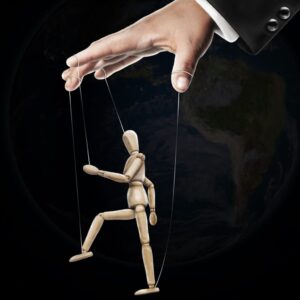 Un pantin en bois et tenu par des ficelles par une main représentant la personne manipulante