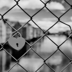 Cadenas en forme de coeur accroché à un grillage symbolisant relations malsaines et enfermantes