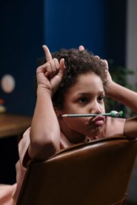 Un petit garçon retourné sur sa chaise, fais les oreilles d'ânes et grimace pour illustrer les troubles de l'attention