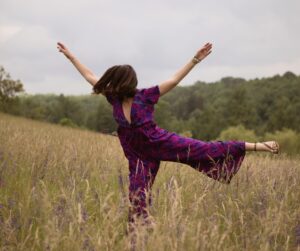 Dans un champ de blé femme saute avec joie dans une tenue colorée avec des couleurs contrastante bleu et rose fushia